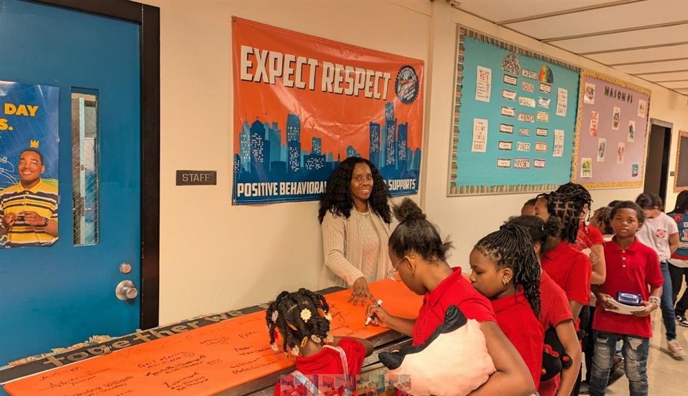  kids signing unity poster with teacher